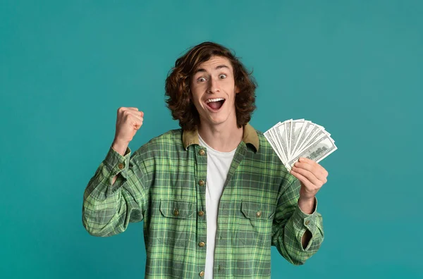 Winnend loterijconcept. gelukkig jongeman met geld op turquoise achtergrond — Stockfoto