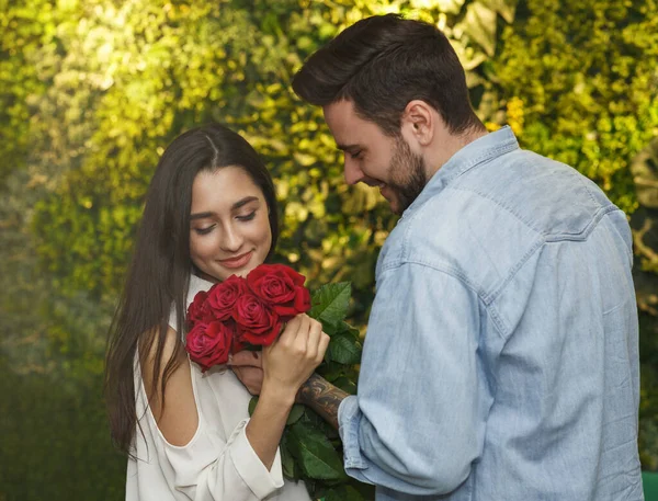 Cara dando rosas vermelhas para namorada namoro no café — Fotografia de Stock