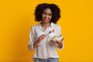 Elinde taze sebze kasesi olan mutlu Afrikalı Amerikalı kadın.