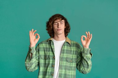 Uyum kavramı. Genç adam meditasyon yapıyor ya da iyi bir jest yapıyor.