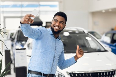 Happy Man Making Selfie Near Automobile Gesturing Thumbs-Up In Dealership