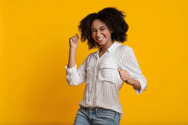 Euforica ragazza nera che celebra il successo, alzando le mani con pugni serrati — Foto Stock