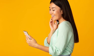 Smiling Chinese Girl Holding Smartphone Reading Message, Studio Shot
