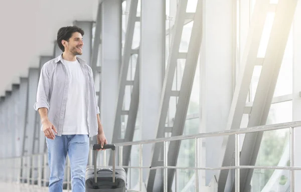 Jovem bonito com mala andando no terminal, indo para o portão — Fotografia de Stock