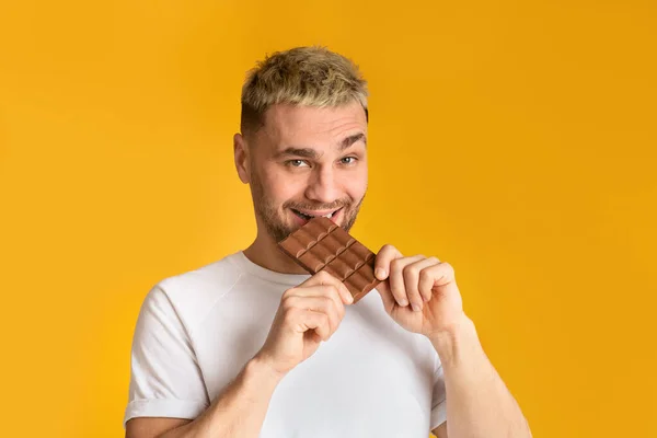 Comida pouco saudável. Homem milenar irônico comendo chocolate — Fotografia de Stock