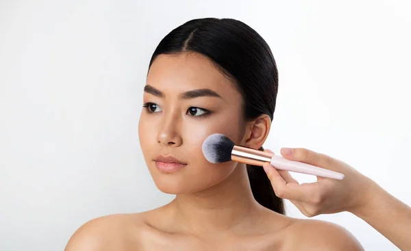 Chinese Girl Using Brush Applying Face Powder On White Background — Zdjęcie stockowe