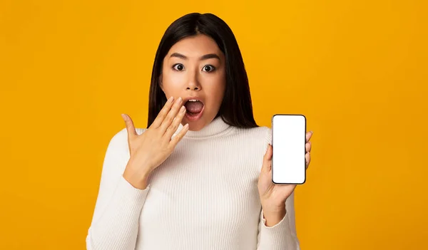 Excited Asian Girl Showing Smartphone Blank Screen On Yellow Background — Stok fotoğraf