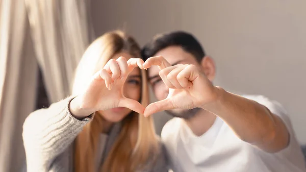 Loving young family of two making heart with their fingers at home, focus on hands — Stok fotoğraf