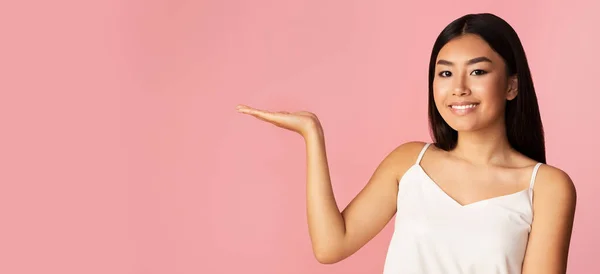 Chinese Model Girl Advertising Invisible Object Standing On Pink Background — стокове фото