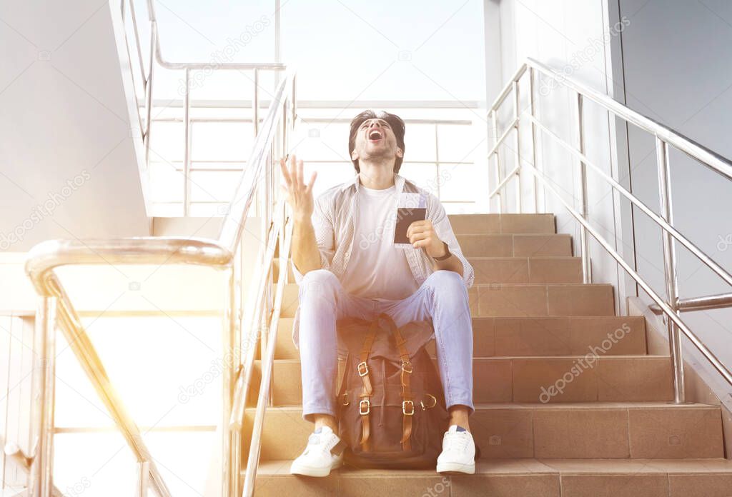 Flight Cancellation. Desperate Man Sitting On Stairs In Airport And Shouting