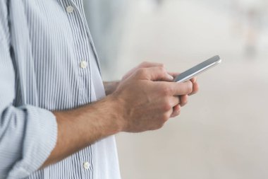 Modern communication concept. Unrecognizable man using smartphone over blurred background, cropped