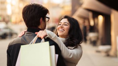 Young loving couple hugging on the street after shopping
