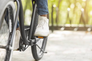 Feet On Pedals Of Unrecognizable Black Man Riding Bicycle In Park