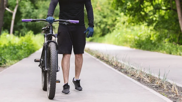 Cropped image of cycler holding bike in public park — Zdjęcie stockowe