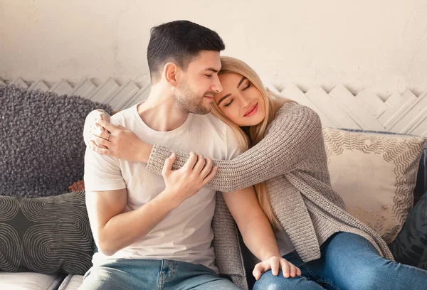 Happy man and woman embracing on sofa in living room — 图库照片