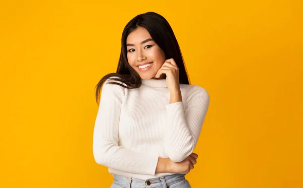 Ragazza asiatica in posa toccando faccia sorridente alla macchina fotografica, Studio Shot — Foto Stock