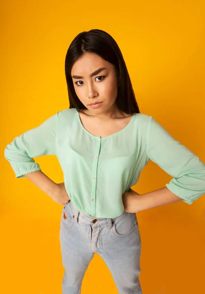 Displeased Asian Girl Posing With Hands On Hips, Yellow Background — Zdjęcie stockowe