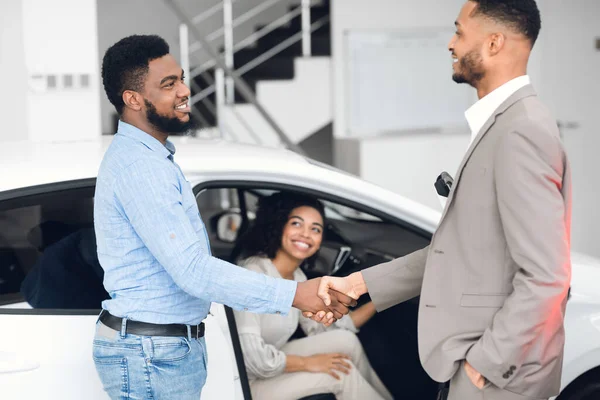 Vendedor de carro apertando as mãos com os compradores após negócio bem sucedido dentro de casa — Fotografia de Stock