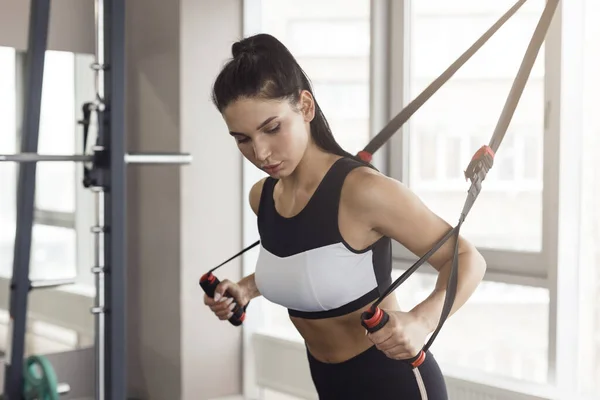 Mujer encantadora usando la máquina de cable en el club deportivo — Foto de Stock