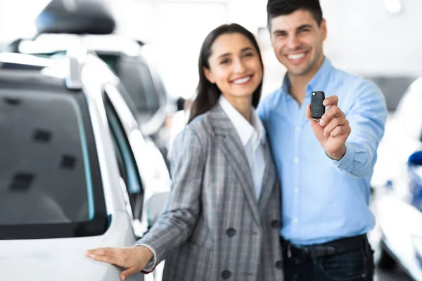 Pareja mostrando la llave del coche de pie en tienda de concesionarios — Foto de Stock