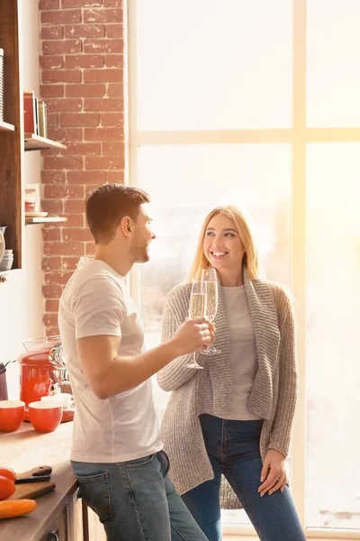 Láska je ve vzduchu. Muž a žena se šampaňským slaví dovolenou v sluncem zalité kuchyni, prázdné místo — Stock fotografie
