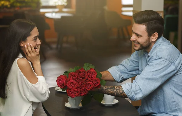 Boyfriend Giving Surprised Girlfriend Beautiful Bouquet Of Roses In Cafeteria — Stockfoto