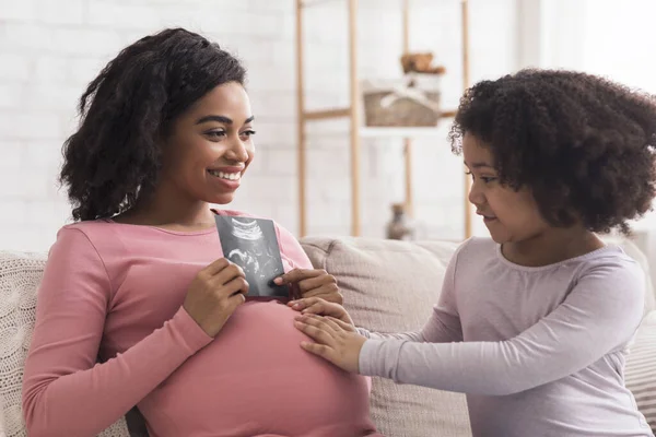 Excited Pregnant Black Woman Showing Baby Ultrasound Scan To Her Daughter — 图库照片