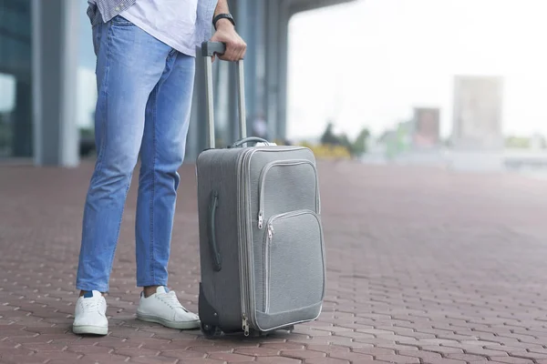 Hombre irreconocible esperando fuera del aeropuerto con maleta — Foto de Stock