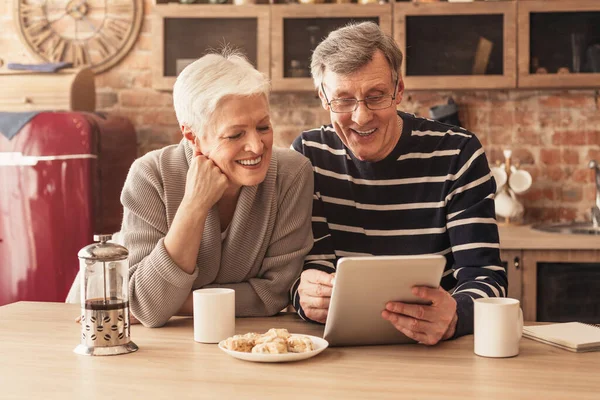 Cheerful Elderly Couple Using Digital Tablet In Kitchen Together — Stock fotografie