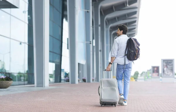 Homem viajante chegou ao aeroporto, andando com mala e mochila ao ar livre — Fotografia de Stock