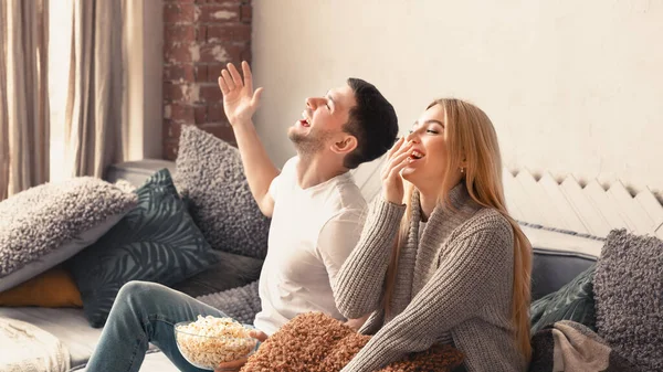 Riendo hombre y mujer disfrutando de la comedia en la televisión en casa, espacio vacío —  Fotos de Stock