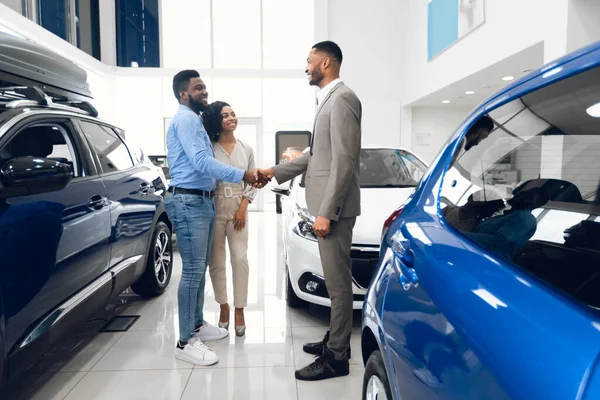 Glückliche Autokäufer beim Händeschütteln mit Verkäufer im Autohaus-Showroom — Stockfoto