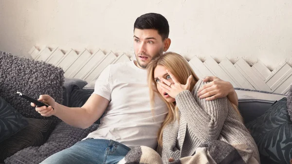 Verängstigtes junges Paar schaut Gruselfilm zu Hause — Stockfoto