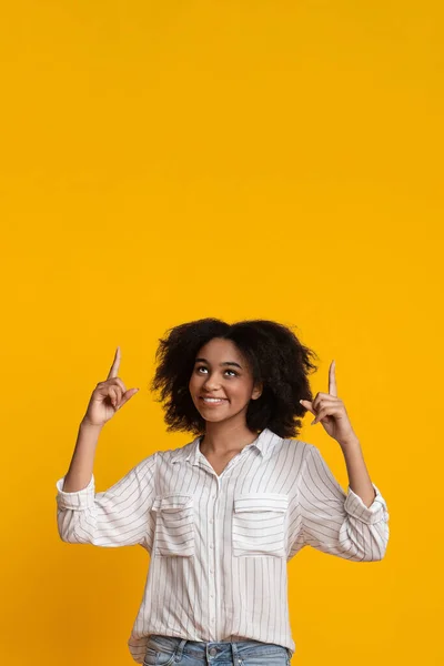 Feliz Afro Girl señalando hacia arriba en el espacio de copia por encima de su cabeza — Foto de Stock