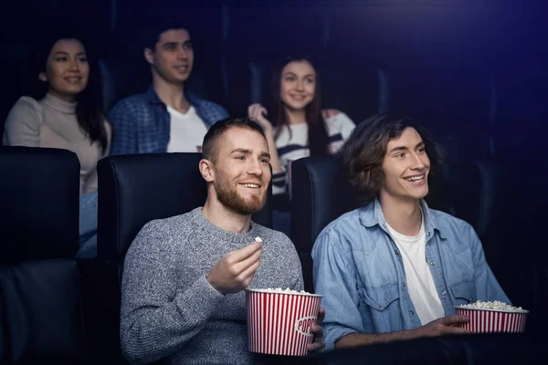 Zábavní koncept. Veselí mladí lidé s popcorn těší film v kině — Stock fotografie