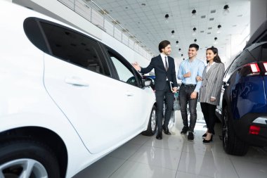 Araba Satış Müdürü galerideki alıcılara otomatik satış gösteriyor
