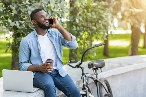 자유 로운 생활 방식. 남자 휴대 전화로 이야기하고, 커피를 마시고, 야외에서 노트북으로 일하는 남자 — 스톡 사진