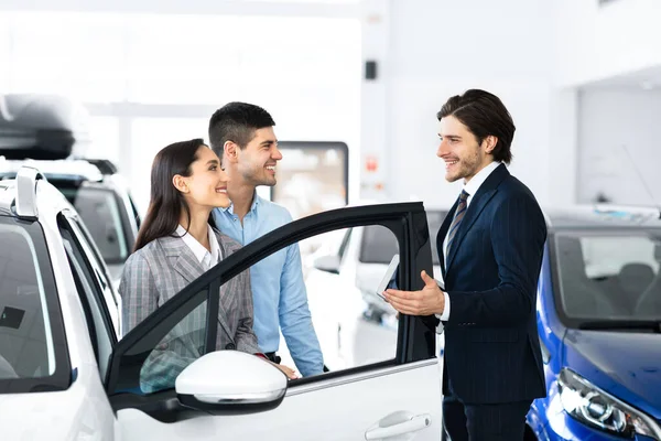 Par väljer bil med professionell återförsäljare i Luxury Dealership Store — Stockfoto