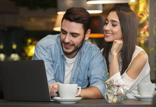 Novio y novia usando el ordenador portátil teniendo café en la cafetería —  Fotos de Stock