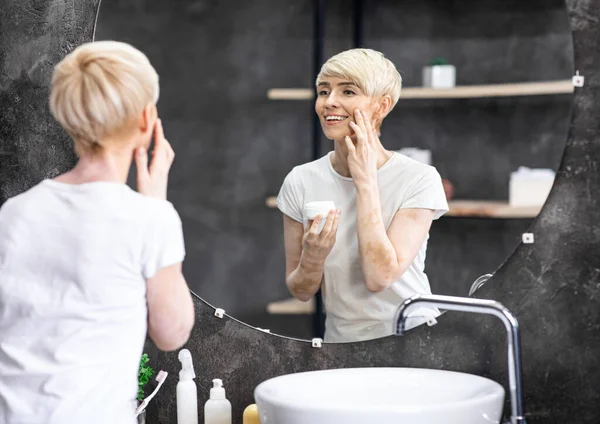 Smiling Woman Applying Cream On Face Standing In Bathroom Indoor — Stock Photo, Image