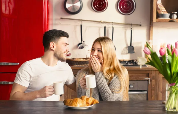 Sevimli kız arkadaş ve erkek arkadaş mutfakta kahve içip kruvasan yiyorlar. — Stok fotoğraf