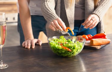 Tanımlanamayan kadın ve erkek mutfakta sağlıklı salata pişiriyor.