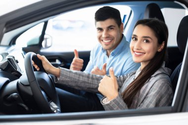 Happy Couple Gesturing Thumbs-Up Sitting In Car