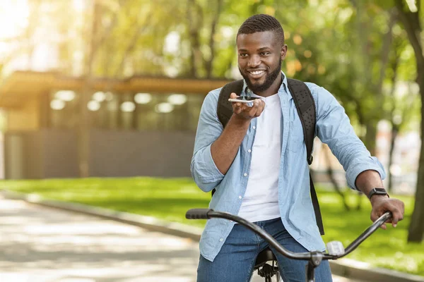Afro cara no bicicleta dando comandos de voz para Smartphone, abertura do navegador — Fotografia de Stock