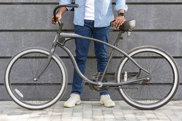 Irreconocible afro hombre sosteniendo bicicleta con diseño elegante — Foto de Stock