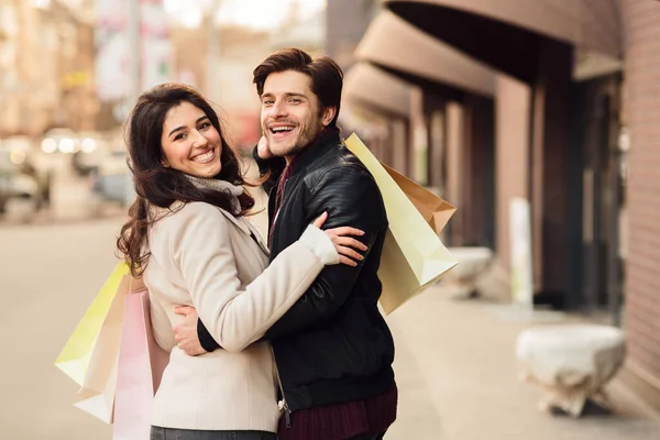 Young loving couple carrying paper shopping bags — Stock Photo, Image