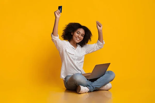 Mujer negra feliz celebrando el éxito con el ordenador portátil y la tarjeta de crédito — Foto de Stock