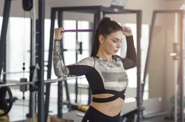 Sporty young girl using elastic band in gym