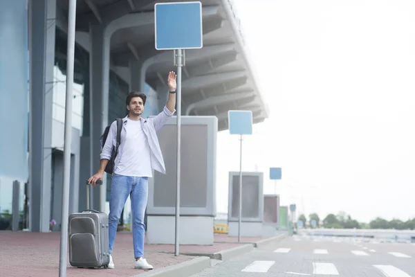 Apanhar um táxi. Homem viajante de pé perto do aeroporto, acenando mão, chamando táxi — Fotografia de Stock