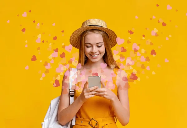 Blonde girl using dating app with flying hearts on smartphone, yellow background — Φωτογραφία Αρχείου